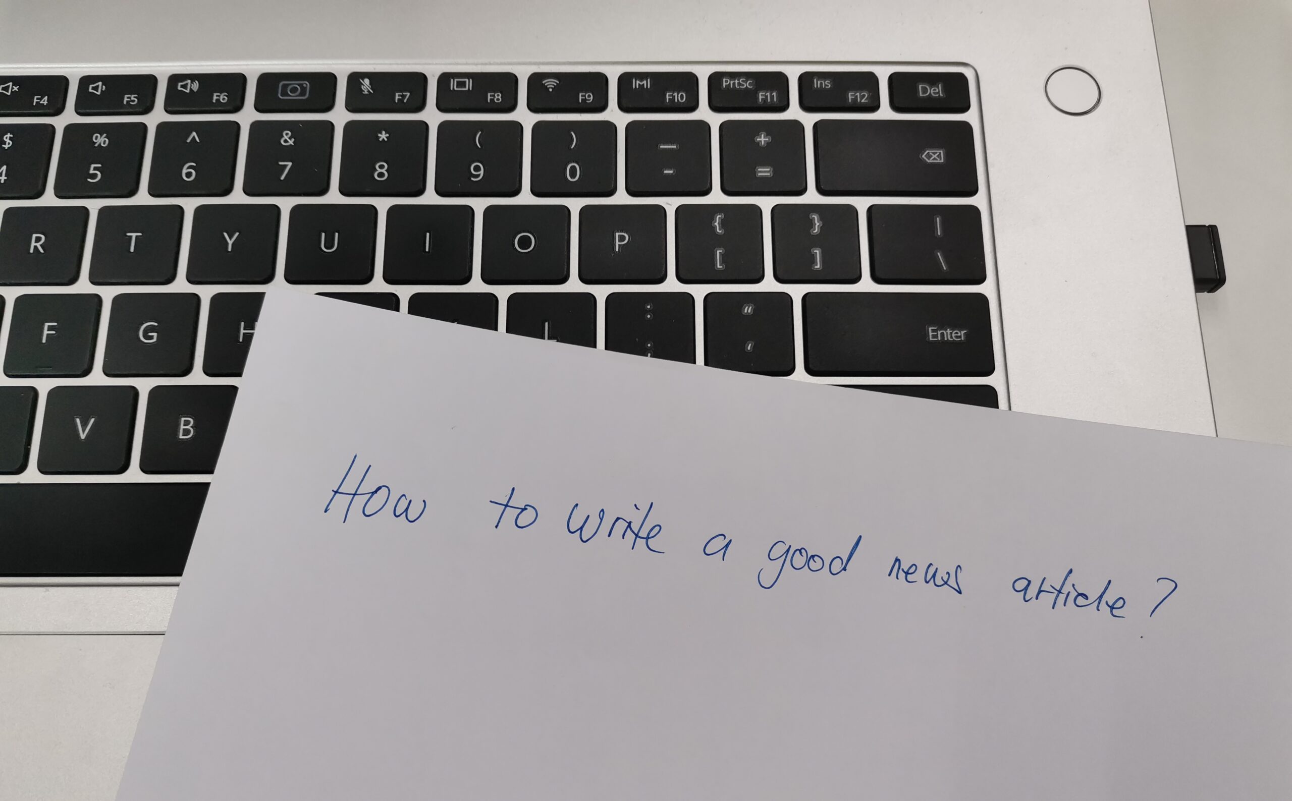 A blank white paper with the words 'How to write a good news article?' written in bold black letters.